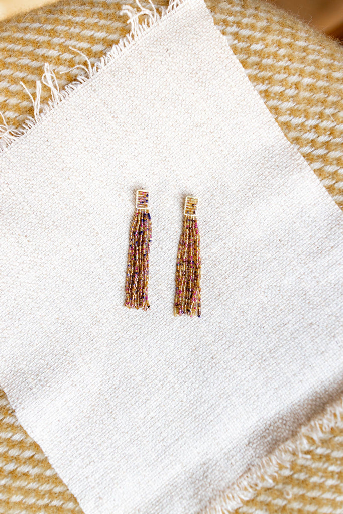 Two earrings on a white napkin with a textured beige background
